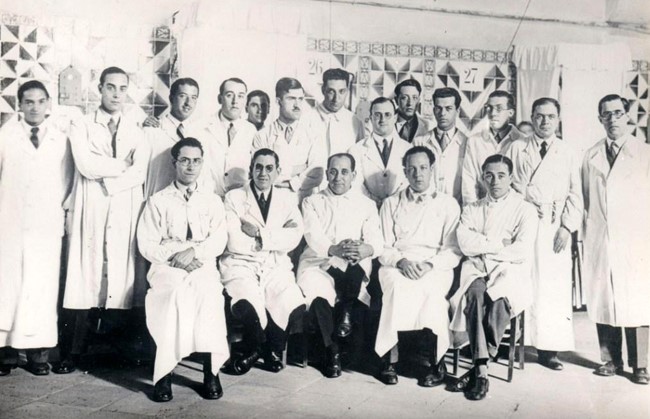 Jaume Pi i Figueras és, assegut, el primer de l'esquerra entre l'equip del Servei de Cirurgia de Manuel Corachan, assegut al centre. A la seva esquerra, Josep Trueta. Hospital de Sant Pau de Barcelona