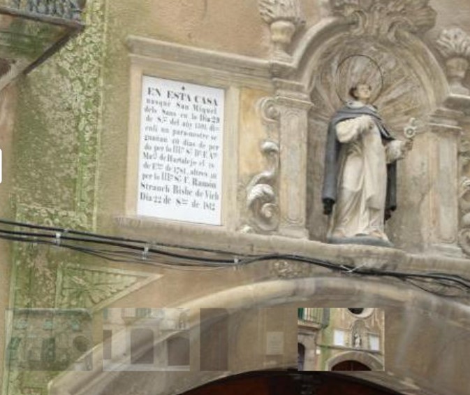 Escultura de Sant Miquel al damunt de la porta de la casa nadiua, on es veu a la façana la descripció que és la casa on va néixer el sant