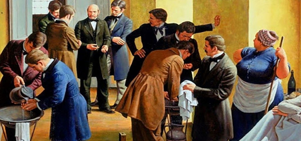 Semmelweis amb tres estudiants al fons de la imatge, fent rentar-se les mans als estudiants que venen de la sala d’autòpsies